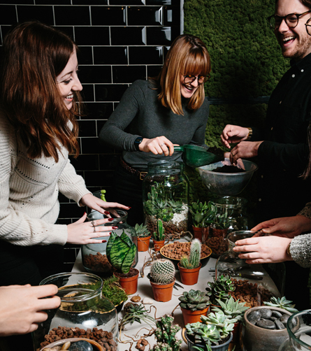 A group of people at a workshop table with plants