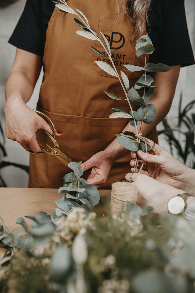 Hands making a garland with eucalyptus